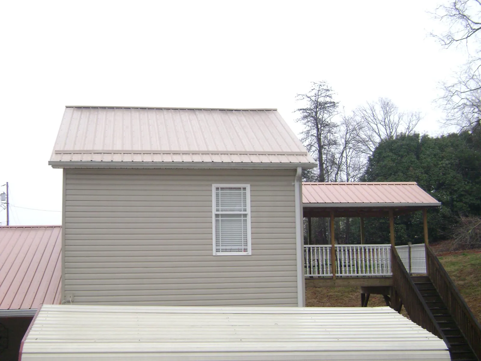 Tan metal roofs on a two story addition and attached porch, from a Roof Replacement job in Ocean Springs
