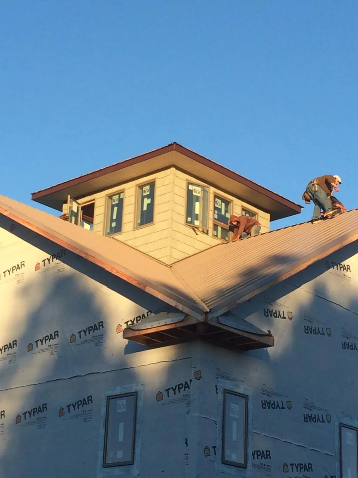 Roofers working around a rooftop cupola on a new metal roof at sunset — Roof Waterproofing in Ocean Springs by Roofing Brothers